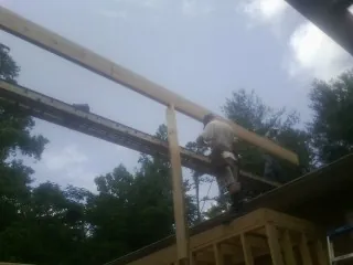 Carpenter setting a ridge beam over a new addition frame — Ice Dam Removal by Roofing Brothers in Granger