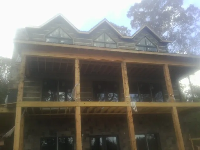 Dormers and porch framing on a large log home under construction — Roof Coating work by our crew in Granger